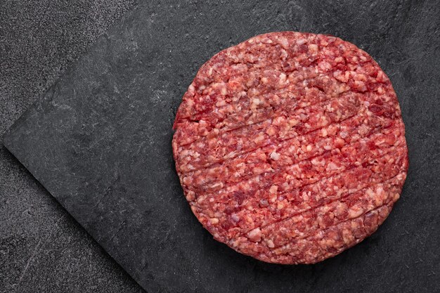 Photo juicy raw burger patty against a dark backdrop