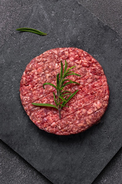 Photo juicy raw burger patty against a dark backdrop