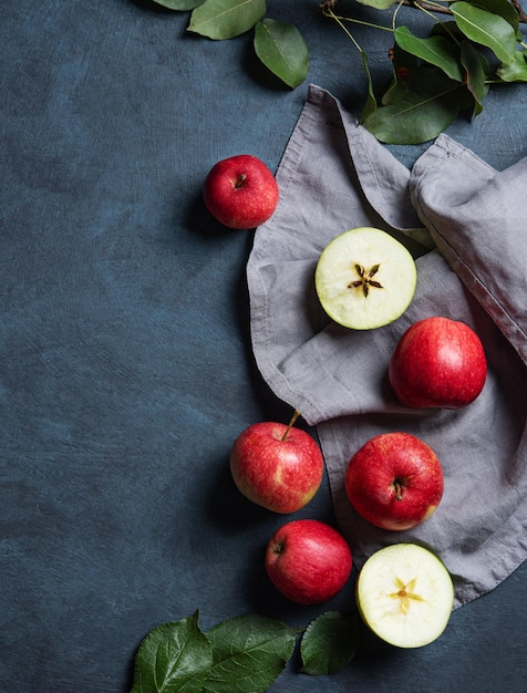 Juicy red apples with leaves on a gray napkin on a dark blue background The concept of autumn healthy food Top view and copy space