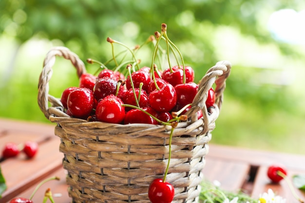 Juicy red cherries in a wicker basket on a wooden table closeup