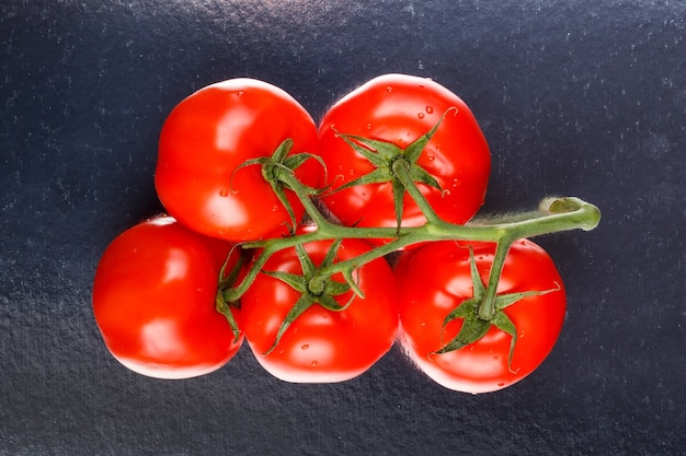 Juicy red tomatoes on a branch on a mirror stand