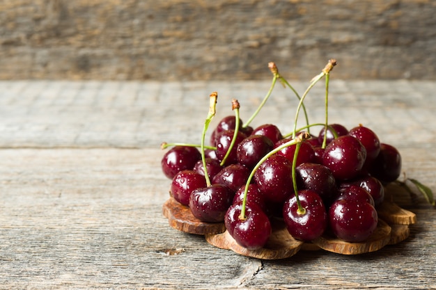 Juicy ripe cherries with twigs on wooden stand on rustic wood