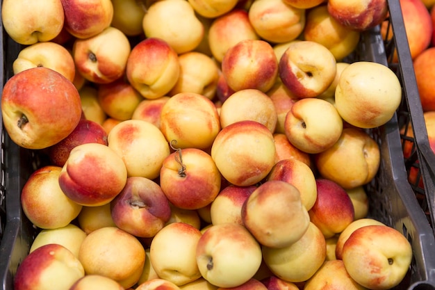 Juicy ripe nectarines in a box in a store Fruit and vegetable department in the supermarket Vitamins and healthy food Closeup