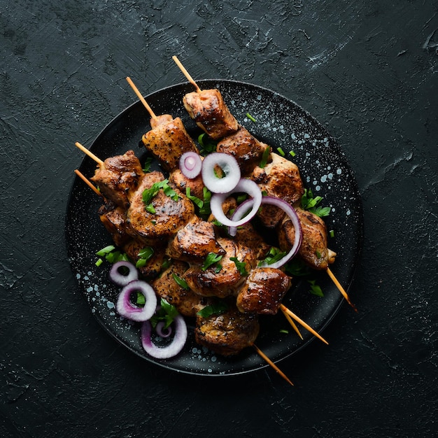 Juicy skewers of meat in a black plate Barbecue kebab Top view Free copy space