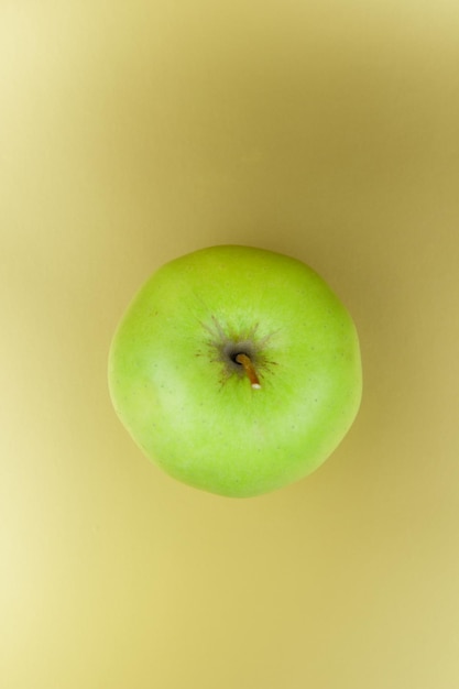 Juicy sweet green apple on a golden background Healthy food concept Closeup of a green fruit View from above