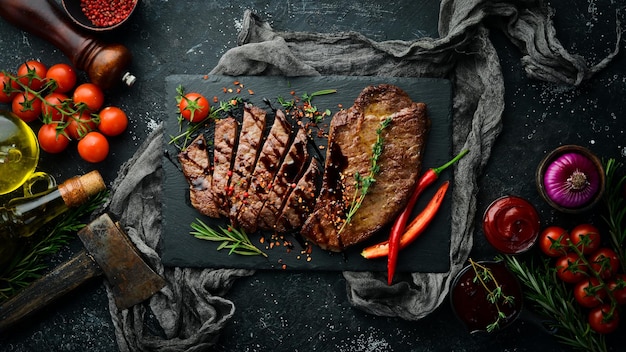 Juicy veal steak with spices thyme and rosemary Top view Flat lay top view on black stone cutting table