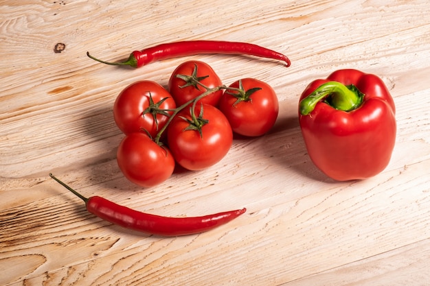 Juicy vegetables, bell peppers and chili peppers and tomatoes on a wooden table. 