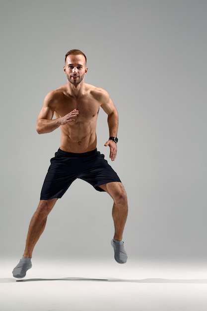 In jump Caucasian professional sportsman training isolated on white studio background Muscular sportive man practicing Copyspace Concept of action motion youth healthy lifestyle