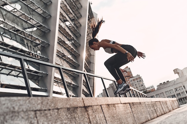 Jumping higher. Full length of modern young woman in sports clothing jumping while exercising outdoors