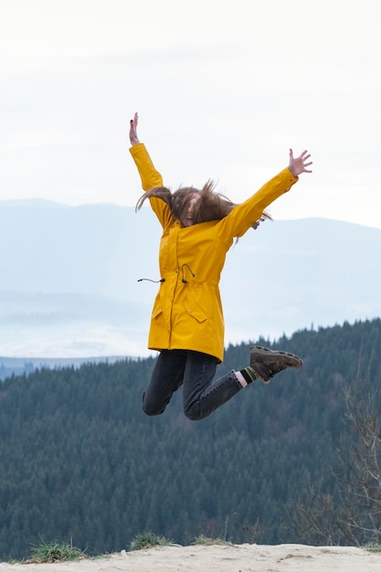 Jumping young woman on top of mountain Happy tourist woman conquered the top Concept of freedom