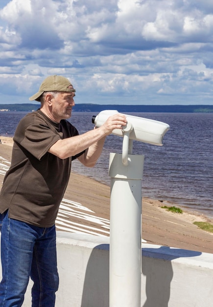 On June 19 2022 in Cheboksary a man looks through a binocular telescope for tourists on the embankment