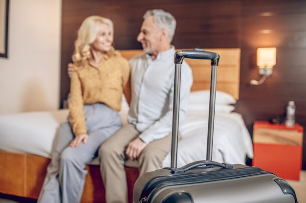 Just arrived. Good-looking couple sitting on a bed in in a hotel room