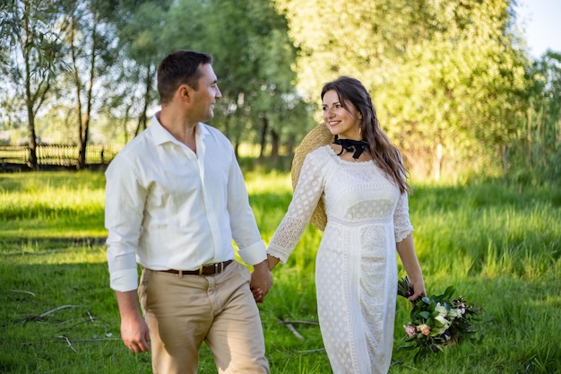 Just married loving hipster couple in wedding dress and suit on a green field in the woods happy bride and groom walking running and dancing on a summer meadow Romantic married to a young family