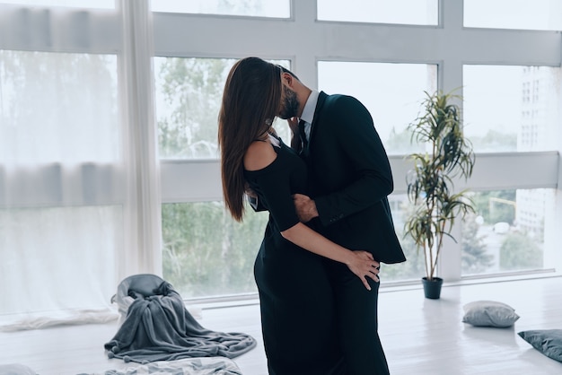 Just one more kiss. Beautiful young couple kissing and embracing while standing time in the bedroom