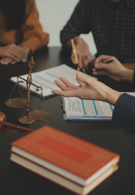 Justice and Law concept Legal counsel presents to the client a signed contract with gavel and legal law or legal having team meeting at law firm in background