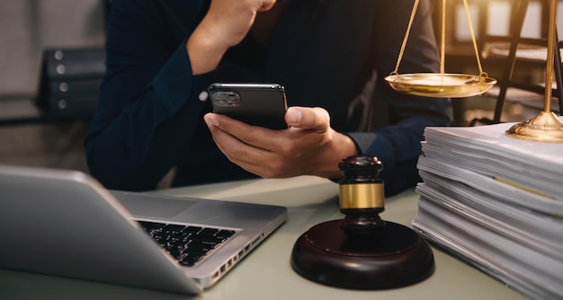 Justice and law conceptMale judge in a courtroom the gavel working with smart phone and laptop and digital tablet computer on wood table in morning light xA