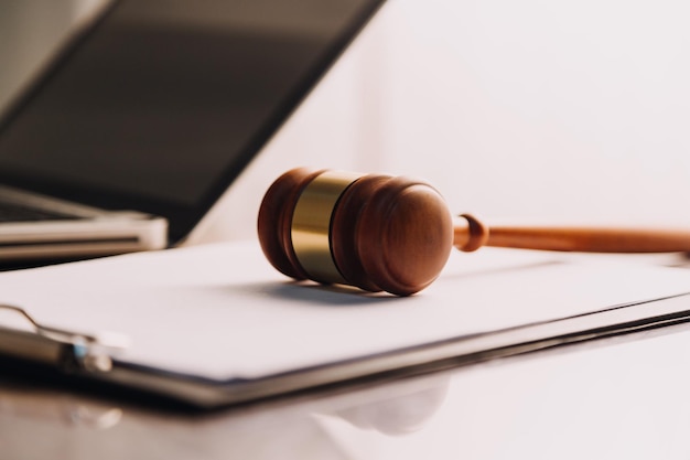 Justice and law conceptMale judge in a courtroom with the gavel working with computer and docking keyboard eyeglasses on table in morning light