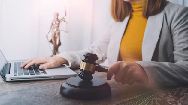 Justice and law conceptMale judge in a courtroom with the gavel working with computer and docking keyboard eyeglasses on table in morning light