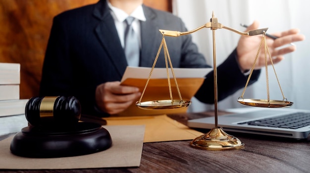 Justice and law conceptMale judge in a courtroom with the gavel working with computer and docking keyboard eyeglasses on table in morning light