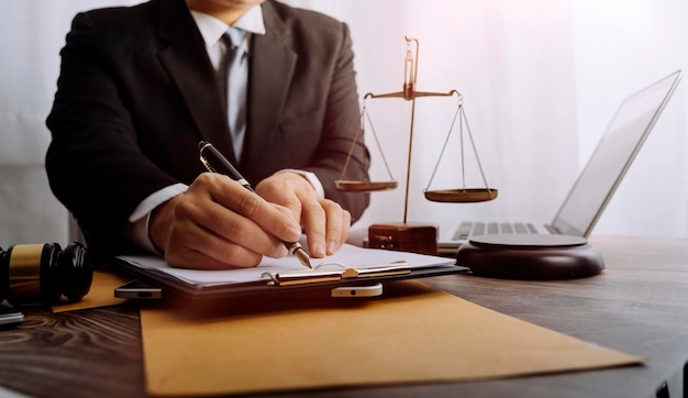 Justice and law conceptMale judge in a courtroom with the gavel working with computer and docking keyboard eyeglasses on table in morning light