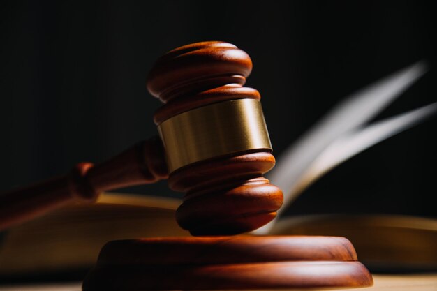 Justice and law conceptMale judge in a courtroom with the gavel working with computer and docking keyboard eyeglasses on table in morning light