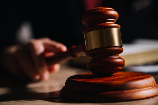 Justice and law conceptMale judge in a courtroom with the gavel working with computer and docking keyboard eyeglasses on table in morning light