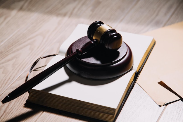 Justice and law conceptMale judge in a courtroom with the gavel working with computer and docking keyboard eyeglasses on table in morning light