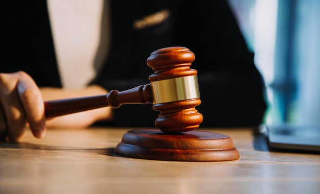 Justice and law conceptMale judge in a courtroom with the gavel working with computer and docking keyboard eyeglasses on table in morning light