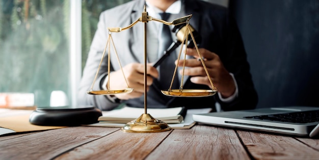 Justice and law conceptMale judge in a courtroom with the gavel working with computer and docking keyboard eyeglasses on table in morning light