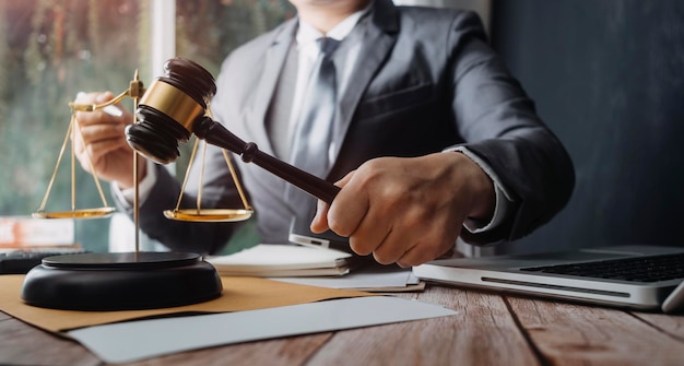 Justice and law conceptMale judge in a courtroom with the gavel working with computer and docking keyboard eyeglasses on table in morning light