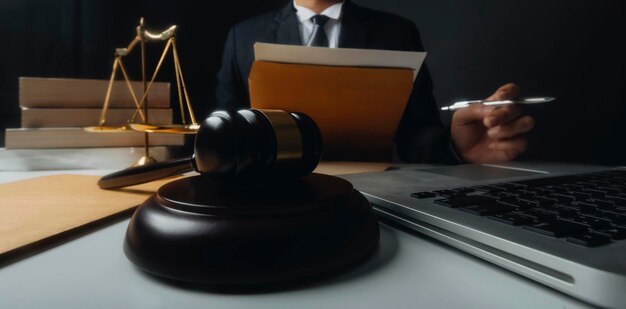 Justice and law conceptMale judge in a courtroom with the gavel working with computer and docking keyboard eyeglasses on table in morning light