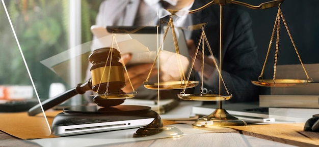 Justice and law conceptMale judge in a courtroom with the gavel working with computer and docking keyboard eyeglasses on table in morning light