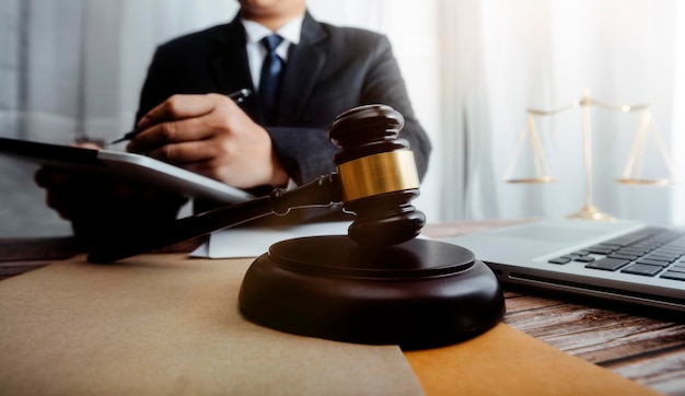 Justice and law conceptMale judge in a courtroom with the gavel working with computer and docking keyboard eyeglasses on table in morning light