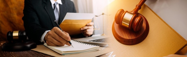 Justice and law conceptMale judge in a courtroom with the gavel working with computer and docking keyboard eyeglasses on table in morning light