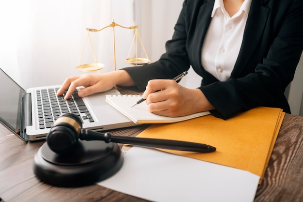 Justice and law conceptMale judge in a courtroom with the gavel working with computer and docking keyboard eyeglasses on table in morning light