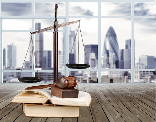 Justice Scales and books and gavel on cityscape background