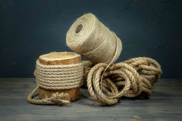 Jute rope and spools of burlap threads or jute twine in closeup on rustic wooden background