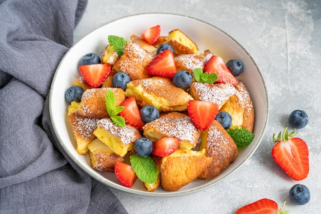 Kaiserschmarrn  traditional austrian pancake dessert with fresh berries and powdered sugar