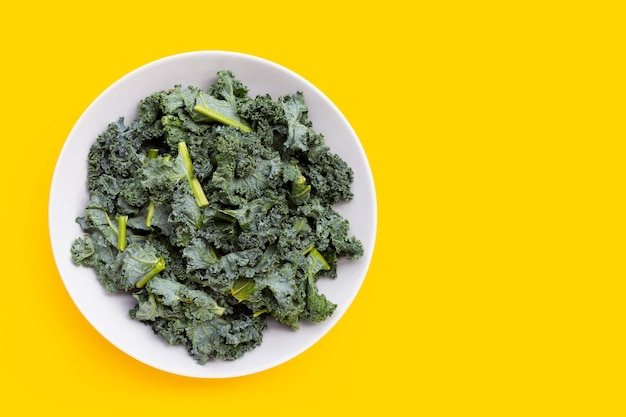 Kale leaves in white plate on yellow background