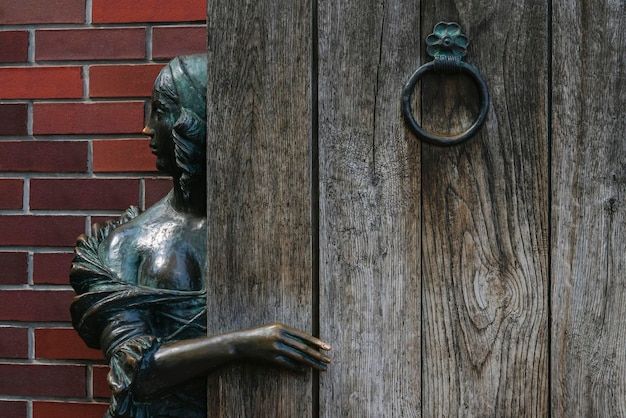 Kaliningrad Russia 06282022 Fragment of the sculpture The Girl behind the door or The Innkeeper in a fishing village on a sunny day