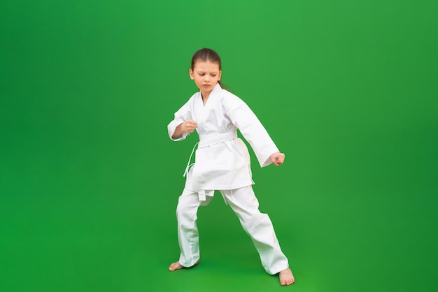 A karate girl does stretching before training in the gym The child is engaged in martial arts