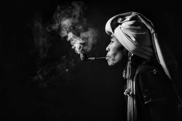 Karen tribal woman smoking opium with a pipe near Chiangmai, Thailand.