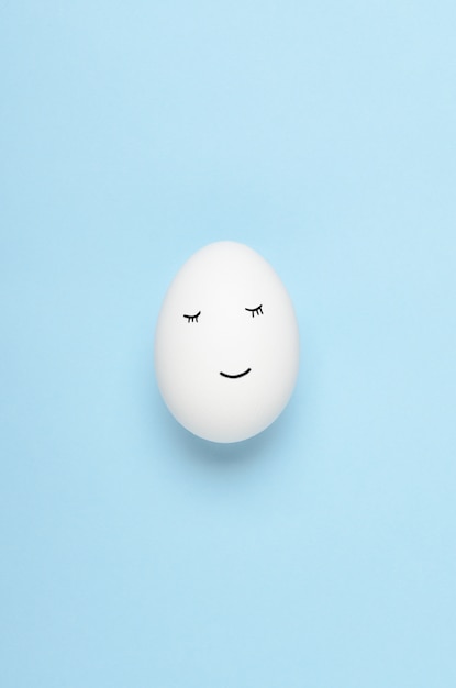 Kawaii faces on white eggs on a blue background. Cartoons, decoration food for children. Top view, flat lay.