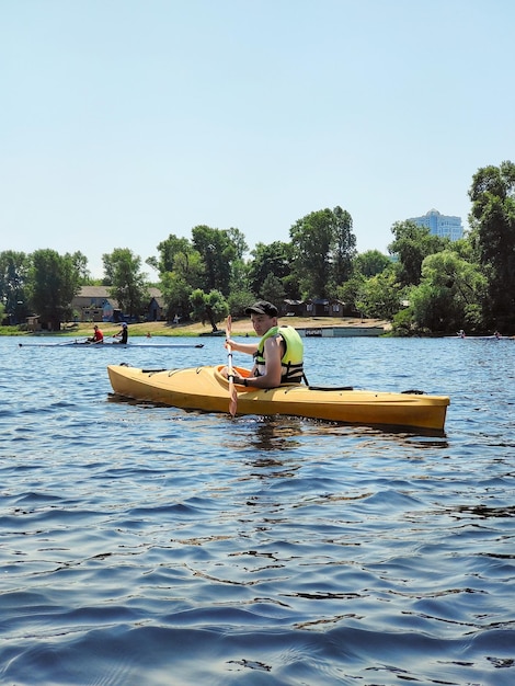 Kayaking A young guy is canoeing on a wide river and smiling Side view Sports tourism and active