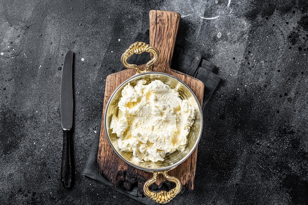 Kaymak Clotted cream butter cream in a rustic pan Black background Top view