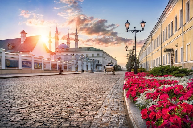 The Kazan Kremlin from the inside overlooking the Kul-Sharif mosque in the rays of the setting sun, a white walking carriage and red flowers