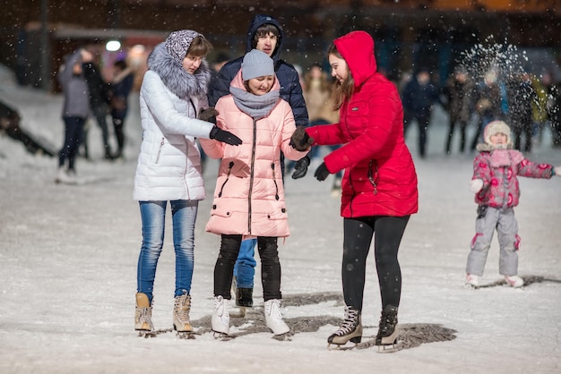 KAZAN RUSSIA 22 JANUARY 2017 Three girls holding hands on skating rink in the evening