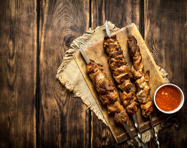 Kebab with tomato sauce. On wooden background.