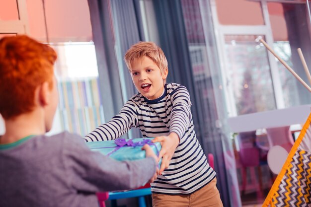 Keep calm. Attentive kid stretching arms while looking at his friend