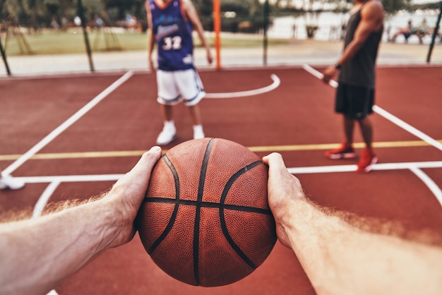 Keep playing. Close up of man holding ball while playing basketball with friends outdoors